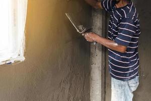 arbeider man's hand- bepleistering een muur met troffel foto