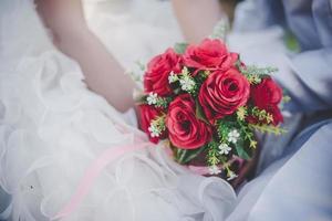 bruid heeft een bruiloft rode roos boeket in handen