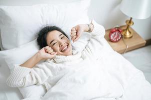 jonge vrouw, gekleed in een wit overhemd, net wakker in bed foto