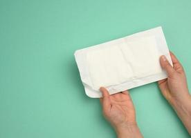 twee vrouw handen houden wit papier verpakking met steriel medisch handschoenen foto