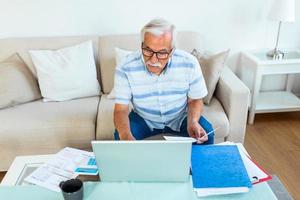 ouderen Mens zittend Aan bankstel Bij huis planning begroting controleren rekeningen cheques, computer, documenten en rekenmachine Aan koffie tafel, dichtbij omhoog bijgesneden concept afbeelding, oud Mens beheren familie onkosten concept foto