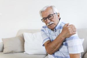 oud senior Mens met schouder pijn. van streek senior ouderling Mens voelen plotseling terug pijn spieren pijn spanning letsel Bij huis, opa aanraken schouder hebben artrose artritis foto