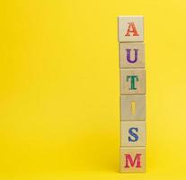 houten kubussen met de opschrift autisme Aan een geel achtergrond. concept van ondersteuning en aanmoediging voor kinderen met ontwikkelingsstoornissen aandoeningen van de hersenen foto