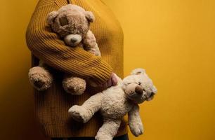 vrouw in oranje gebreid trui knuffels schattig bruin teddy beer. de concept van eenzaamheid en droefheid, depressie foto