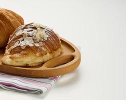 gebakken knapperig croissant Aan houten bord, wit tafel. ontbijt foto