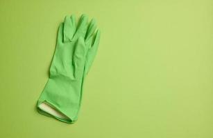 paar- van groen beschermend rubber handschoenen voor schoonmaak Aan een groen pagina foto