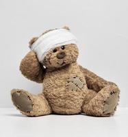 kinderen speelgoed- teddy beer zit met een verbonden hoofd. kinderjaren trauma concept foto