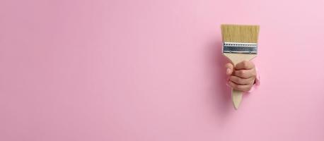 vrouw hand- houden nieuw verf borstel met houten omgaan met Aan een roze achtergrond foto