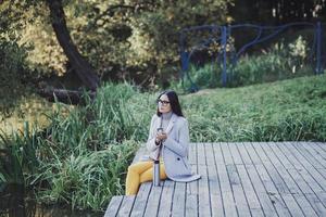 vrouw met een thermosfles zittend in de herfst park foto