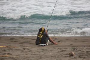 foto van een persoon visvangst Aan de strand