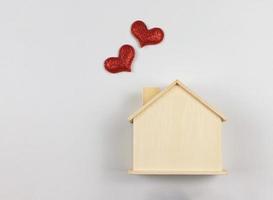 vlak leggen van houten model- huis met rood schitteren harten geïsoleerd Aan wit achtergrond. droom huis , huis van liefde, sterk relatie, valentijnskaarten. foto