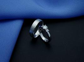 wit goud bruiloft ring. paar ring met glanzend en doff afwerking met blauw en zwart achtergrond foto