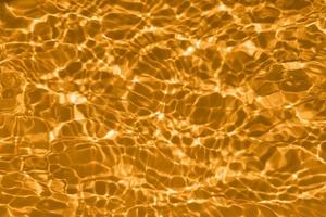 onscherp wazig transparant goud gekleurde Doorzichtig kalmte water oppervlakte structuur met spatten en bubbels. modieus abstract natuur achtergrond. water golven in zonlicht met kopiëren ruimte. geel waterverf schijnen foto
