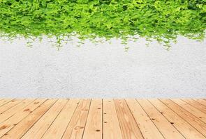 betonnen muur met groene bladeren en houten vloer foto