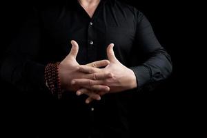 Mens in een zwart overhemd gekruiste zijn vingers en presteert de vajrapradama mudra foto