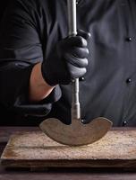 chef in zwart kleren houdt in zijn hand- een metaal oud mes foto
