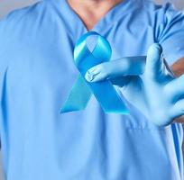 dokter in uniform en latex handschoenen Holding een blauw lint foto