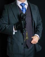 portret van heer in grijs pak Aan zwart achtergrond Holding leer handschoenen. wijnoogst stijl en retro mode. foto