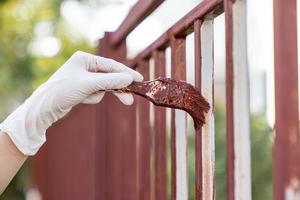 hand- houdt een penseel en verven de schutting, reparatie. foto