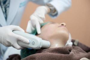 schoonheidsspecialist procedure door elektrisch apparaat, echografie behandeling behandeling voor huid aanscherping in esthetisch kliniek. foto