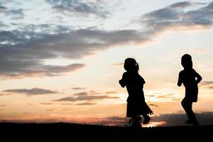 zonsondergang silhouet van spelende kinderen foto