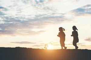 zonsondergang silhouet van spelende kinderen foto