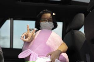 jong meisje dat een masker draagt met een v-teken of vredesteken tijdens covid-19 foto