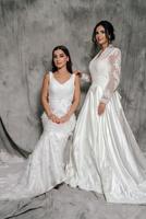 twee meisjes in een bruiloft jurk studio portret Aan een grijs achtergrond foto