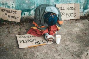 man zit naast de straat met een daklozenbericht foto