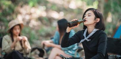 jong Dames juichen en drinken drank voorkant van camping tent foto