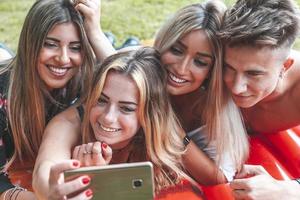 groep van millennial vrienden nemen een selfie buitenshuis aan het liegen in de gras foto