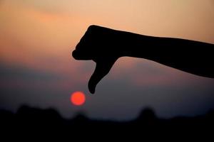 menselijk hand- silhouet maken afkeer teken zonsondergang achtergrond foto