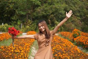 Aziatisch vrouw glimlachen gelukkig tussen mooi bloemen foto