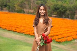 Aziatisch vrouw glimlachen gelukkig tussen mooi bloemen foto