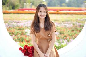 Aziatisch vrouw glimlachen gelukkig tussen mooi bloemen foto