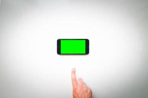 vrouw hand- houdt mobiel smartphone met groen scherm in verticaal positie geïsoleerd Aan groen achtergrond met duimen omhoog vinger. bespotten omhoog mobiel scherm blanco ruimte foto