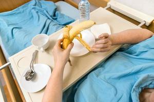 vrouw schillen banaan in thuiszorg ziekenhuis bed foto