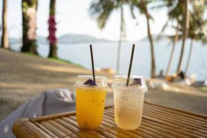twee cups oranje sap Aan top tafel kust cafe vakantie kokosnoot bomen achtergrond. foto