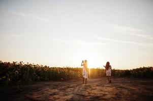 twee mooie jonge zwarte vrienden vrouw dragen zomerjurk poseren in een zonnebloemveld. foto