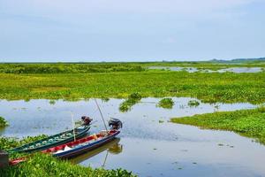 vissers houten boot afgemeerd Aan de kust in een meer in phatthalung foto