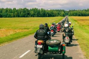 groep van motorrijders ritten Aan asfalt land weg Aan zomer zonnig dag. optocht van motorfietsen. foto