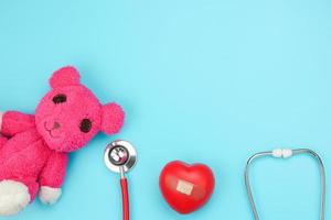 stethoscoop en roze beer op blauwe achtergrond foto