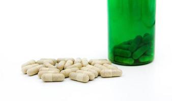 wit pillen of capsule met groen pil fles geïsoleerd Aan wit achtergrond met kopiëren ruimte voor toevoegen tekst. gezond, kruid, houder voorwerp en geneesmiddel. voedsel supplement voor genezen of reparatie Gezondheid foto