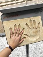 toerist zetten zijn hand- Bij de hong Kong Chinese acteur jacky cheung en beroemdheid hand- prints gedenkteken handtekening Bij de Laan van sterren in hong kong. foto