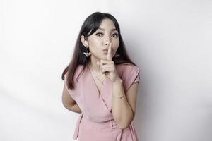 portret van een jong Aziatisch vrouw vertellen worden stil, zwijgen met echt gezicht, stil met vinger ingedrukt naar lippen, geïsoleerd door wit achtergrond foto
