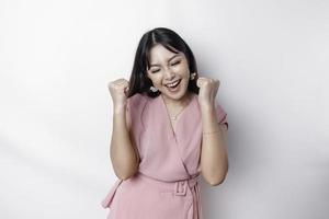 een jong Aziatisch vrouw met een gelukkig geslaagd uitdrukking vervelend roze blouse geïsoleerd door wit achtergrond foto