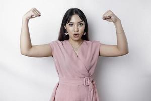opgewonden Aziatisch vrouw vervelend een roze blouse tonen sterk gebaar door hijs- haar armen en spieren glimlachen trots foto