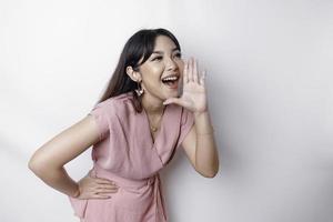 jong mooi vrouw vervelend een roze blouse geschreeuw en schreeuwen luid met een hand- Aan haar mond. communicatie concept. foto