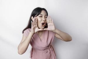jong mooi vrouw vervelend een roze blouse geschreeuw en schreeuwen luid met een hand- Aan haar mond. communicatie concept. foto