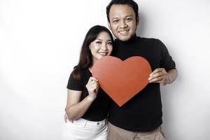 een jong Aziatisch paar glimlachen en Holding rood hartvormig papier, geïsoleerd door wit achtergrond foto